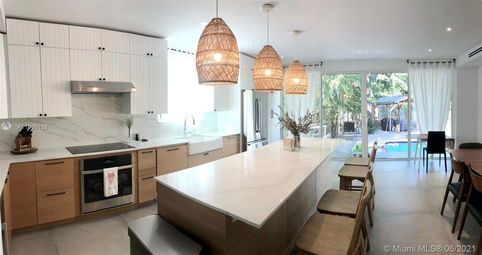 32 Southwest 23rd Road Miami, FL 33129 - Photo 11 of 27 an open kitchen with granite countertop a stove a sink a dining table and chairs with wooden floor