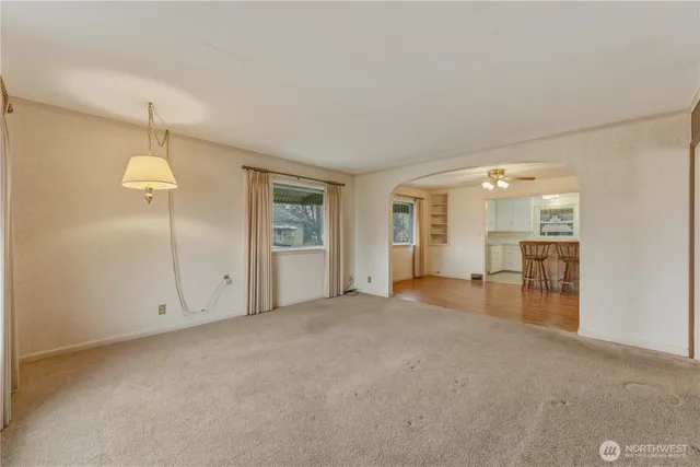 an empty room with chandelier fan and windows