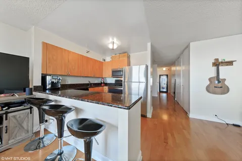 a kitchen with stainless steel appliances granite countertop a table chairs in it and wooden floors