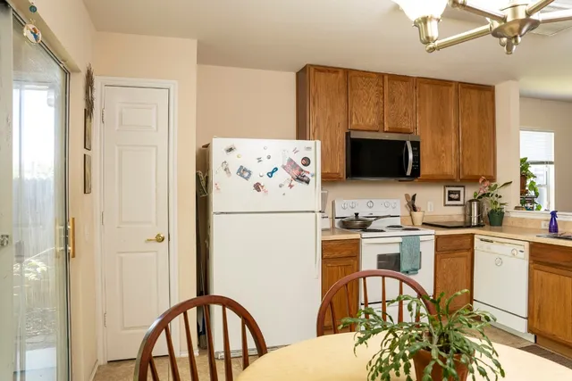 a kitchen with stainless steel appliances a stove a sink dishwasher a refrigerator with a dining table and chairs with wooden floor