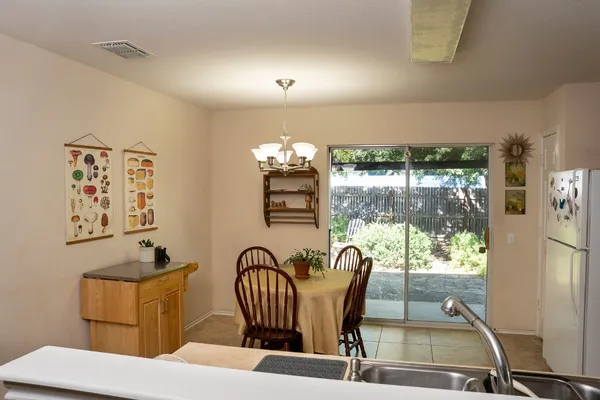 a kitchen with stainless steel appliances a refrigerator a stove a sink a dining table and chairs with wooden floor