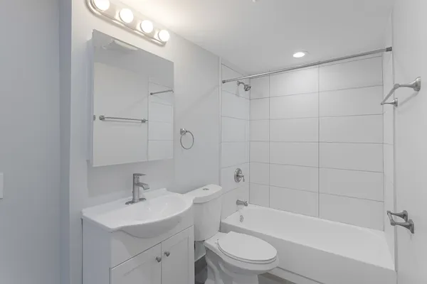 a bathroom with a bathtub shower sink vanity mirror and toilet
