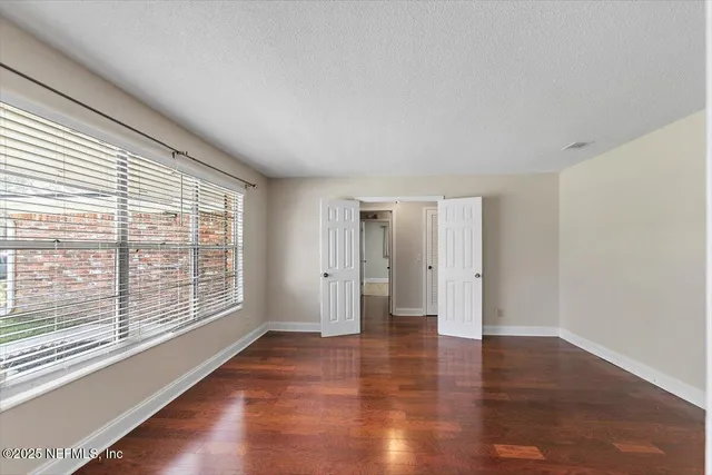 a view of an empty room with wooden floor and a window