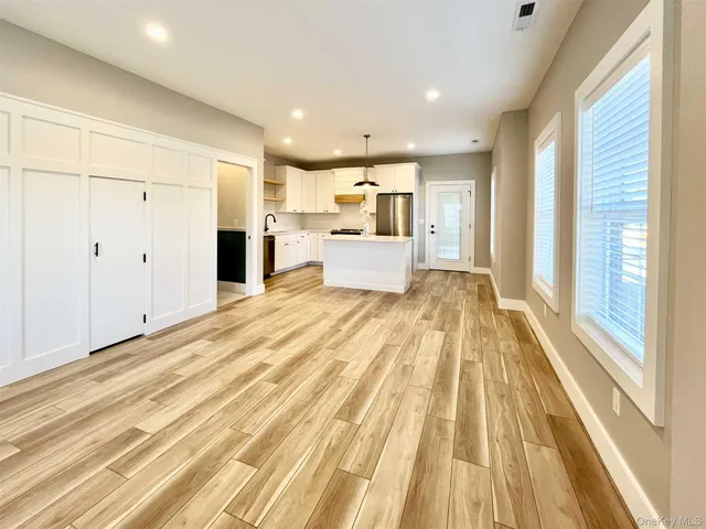 a view of a kitchen with kitchen island stainless steel appliances wooden floor and windows