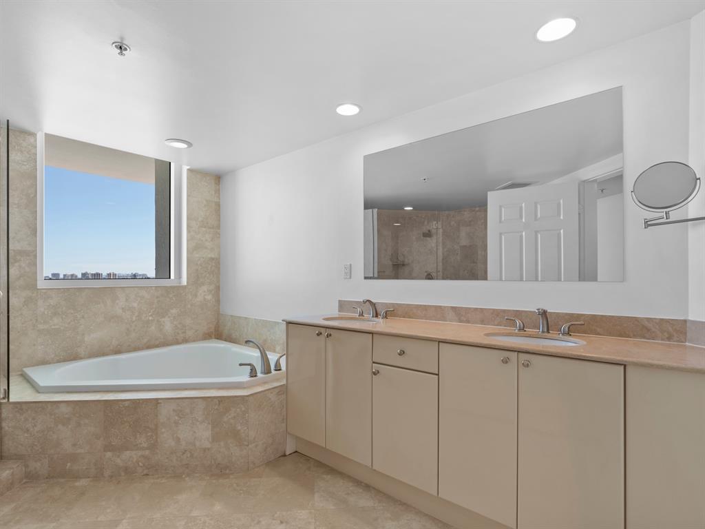 1745 East Hallandale Beach Boulevard, Unit 2007W Hallandale Beach, FL 33009 - Photo 12 of 16 a bathroom with a granite countertop bathtub sink and mirror