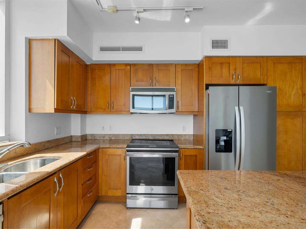 1745 East Hallandale Beach Boulevard, Unit 2007W Hallandale Beach, FL 33009 - Photo 6 of 16 a kitchen with stainless steel appliances granite countertop a sink a stove and a refrigerator