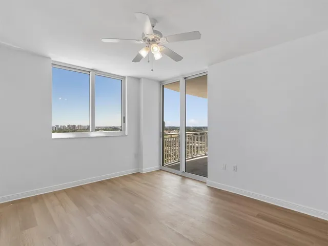 a view of an empty room with wooden floor and a large mirror