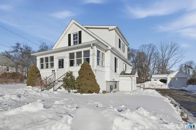 a view of a white house with a yard covered in snow