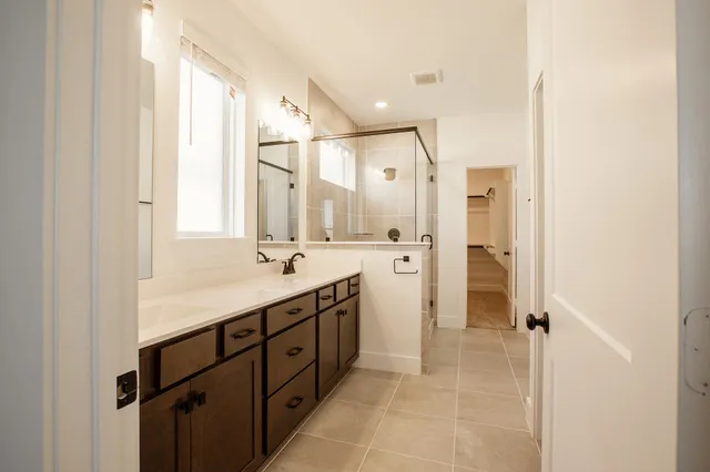 a spacious bathroom with a double vanity sink a mirror and a shower