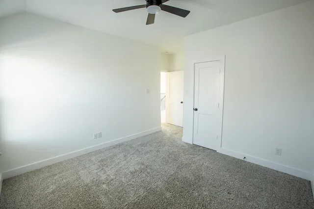 an empty room with a ceiling fan and carpet