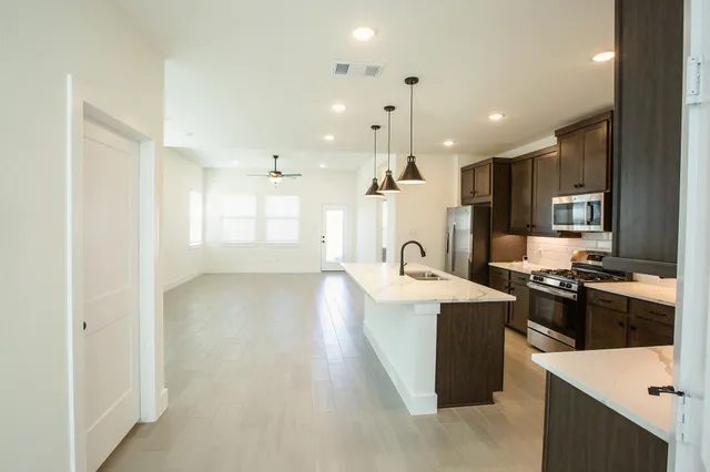 a large kitchen with stainless steel appliances kitchen island a stove a refrigerator a oven and a sink with large countertops