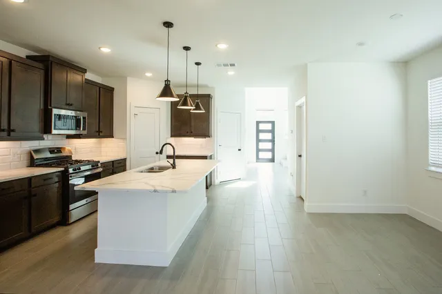 a kitchen with stainless steel appliances kitchen island granite countertop a sink stove and refrigerator