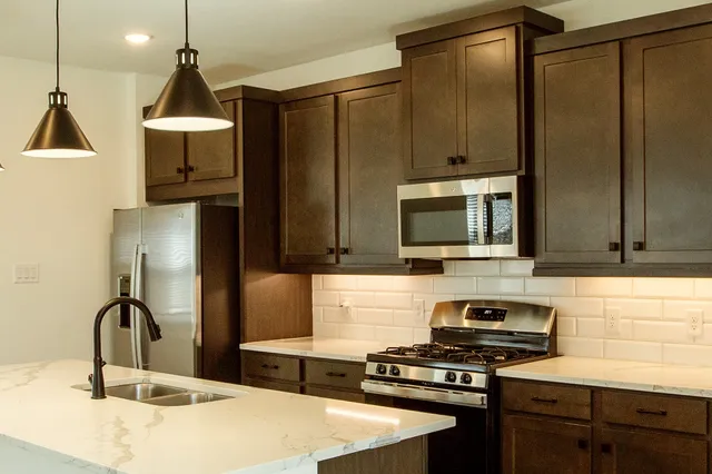 a kitchen with stainless steel appliances granite countertop a stove a sink and a microwave