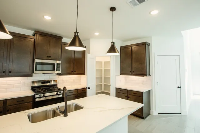 a kitchen with stainless steel appliances kitchen island a stove and a sink