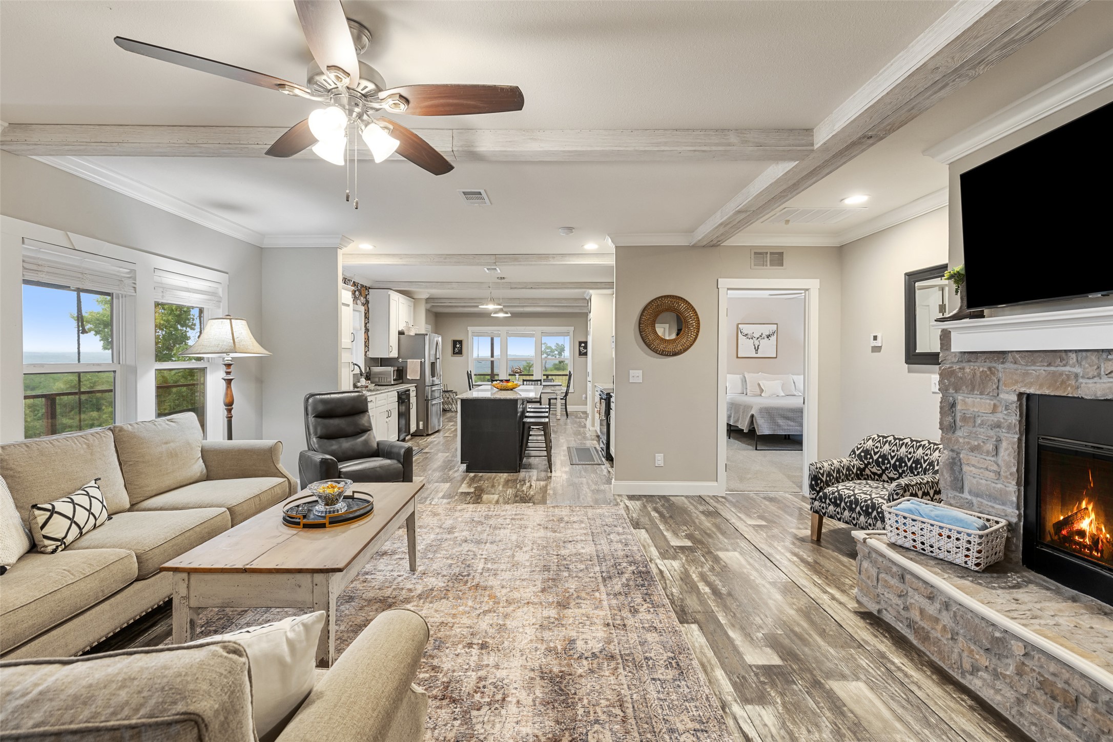 830 Ulrich Road Johnson City, TX 78636 - Photo 25 of 40 An inviting open-concept living space features an exposed beam ceiling, fireplace, and scenic window views.