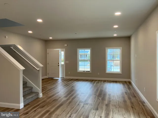 a view of an empty room with wooden floor and stairs