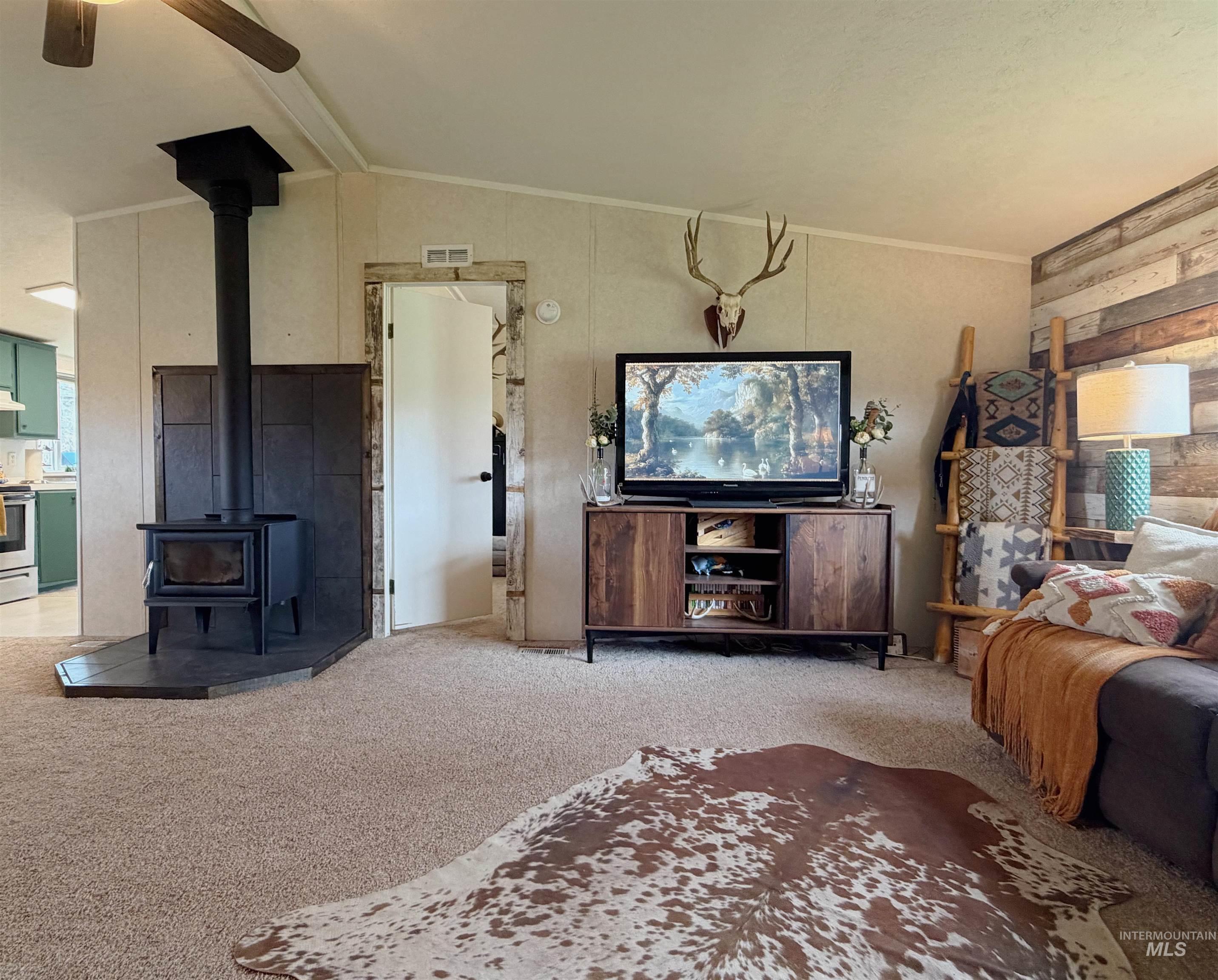 2605 West Frk Road Council, ID 83612 - Photo 16 of 34 Living room with light colored carpet, a wood stove, ceiling fan, lofted ceiling, and crown molding