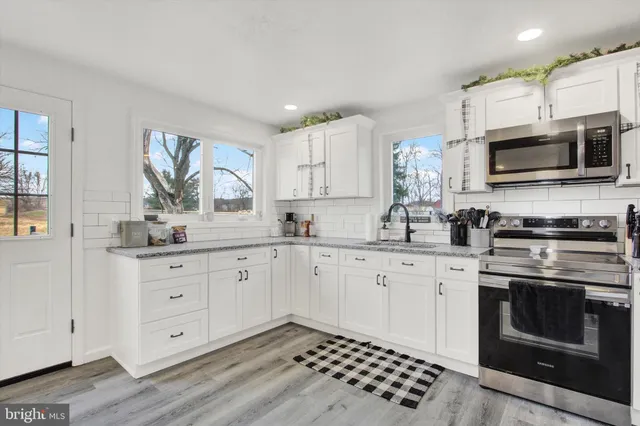 a kitchen with stainless steel appliances white cabinets a sink and a stove