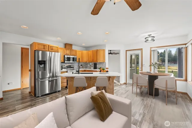 a living room with stainless steel appliances furniture and a kitchen view