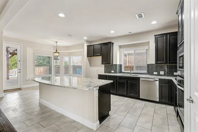 a large kitchen with granite countertop a stove and cabinets