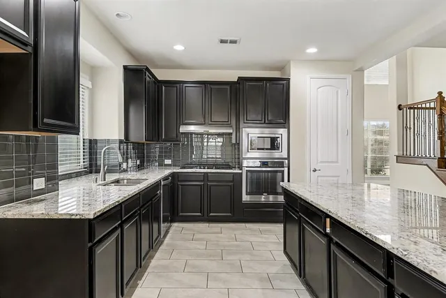 a kitchen with kitchen island granite countertop a sink stove and refrigerator