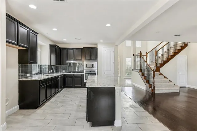 a large kitchen with stainless steel appliances granite countertop a refrigerator and a sink