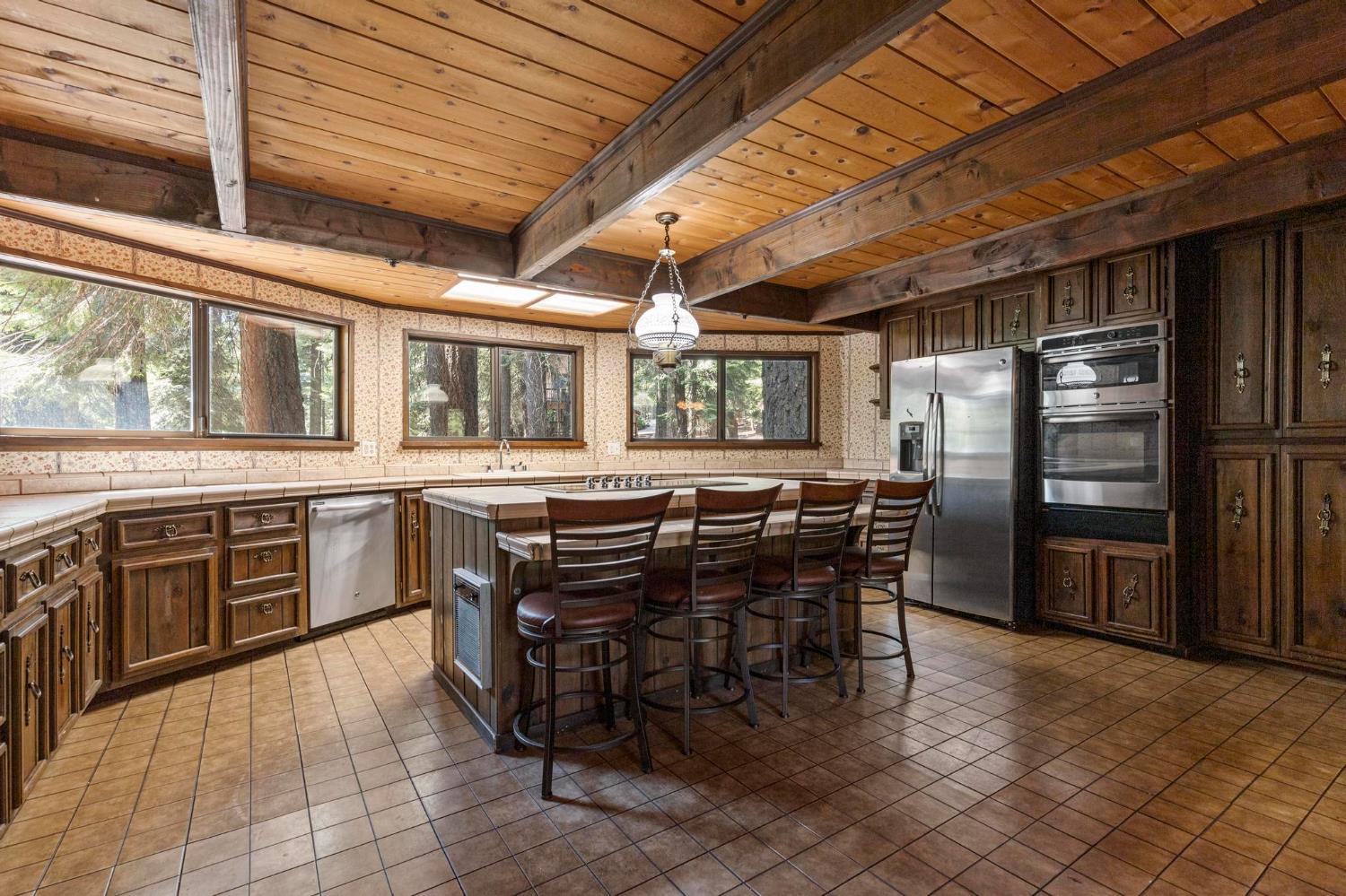 1131 Lake Ridge Road Lake Almanor, CA 96137 - Photo 14 of 55 a kitchen with stainless steel appliances a stove a sink a dining table and chairs with wooden floor
