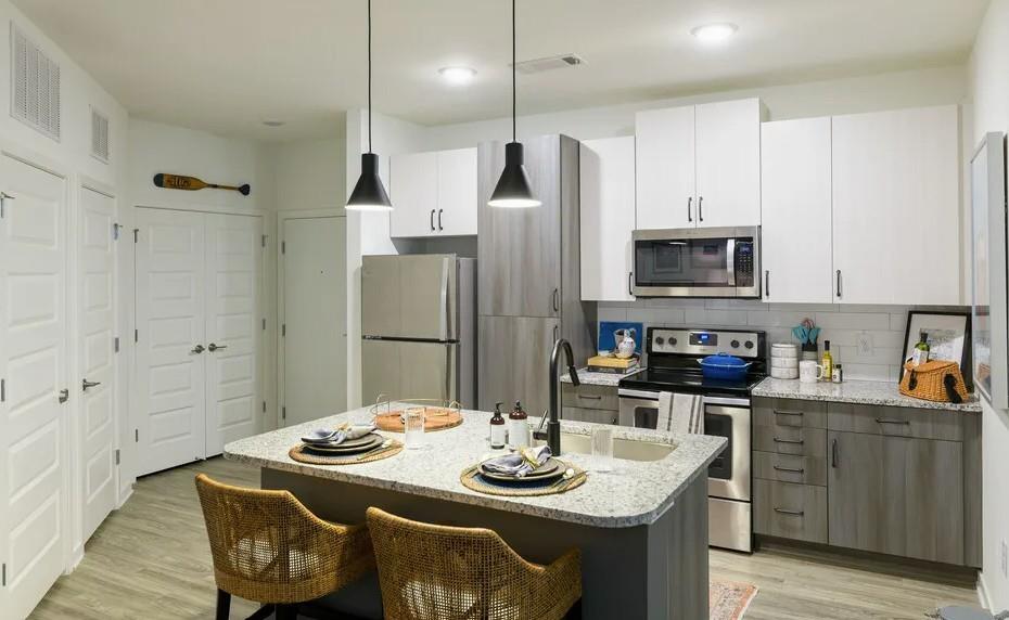 a kitchen with stainless steel appliances kitchen island granite countertop a sink a refrigerator and a stove