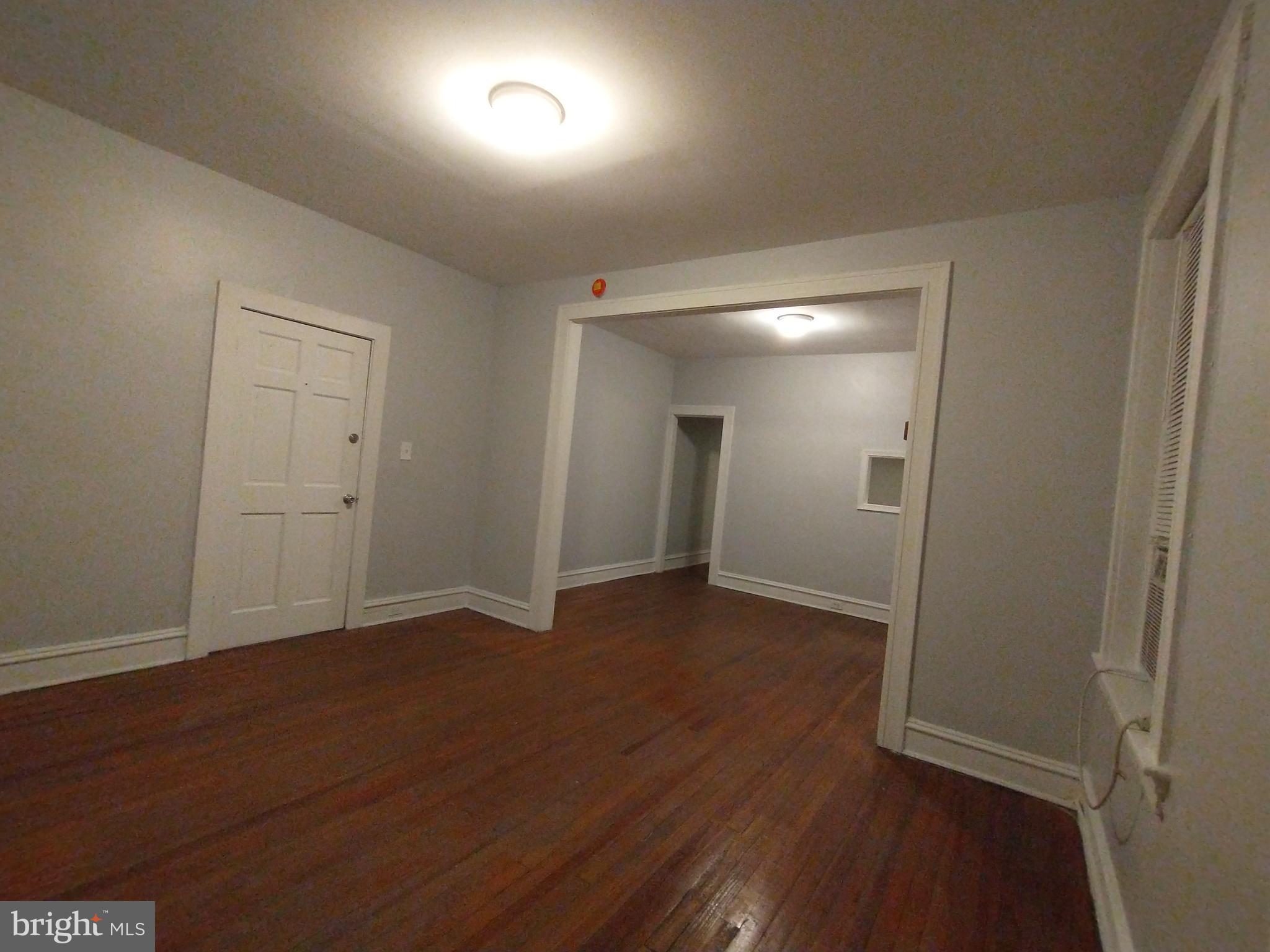 307 Dolphin Street, Unit 3C Baltimore, MD 21201 - Photo 3 of 14 an empty room with wooden floor and windows