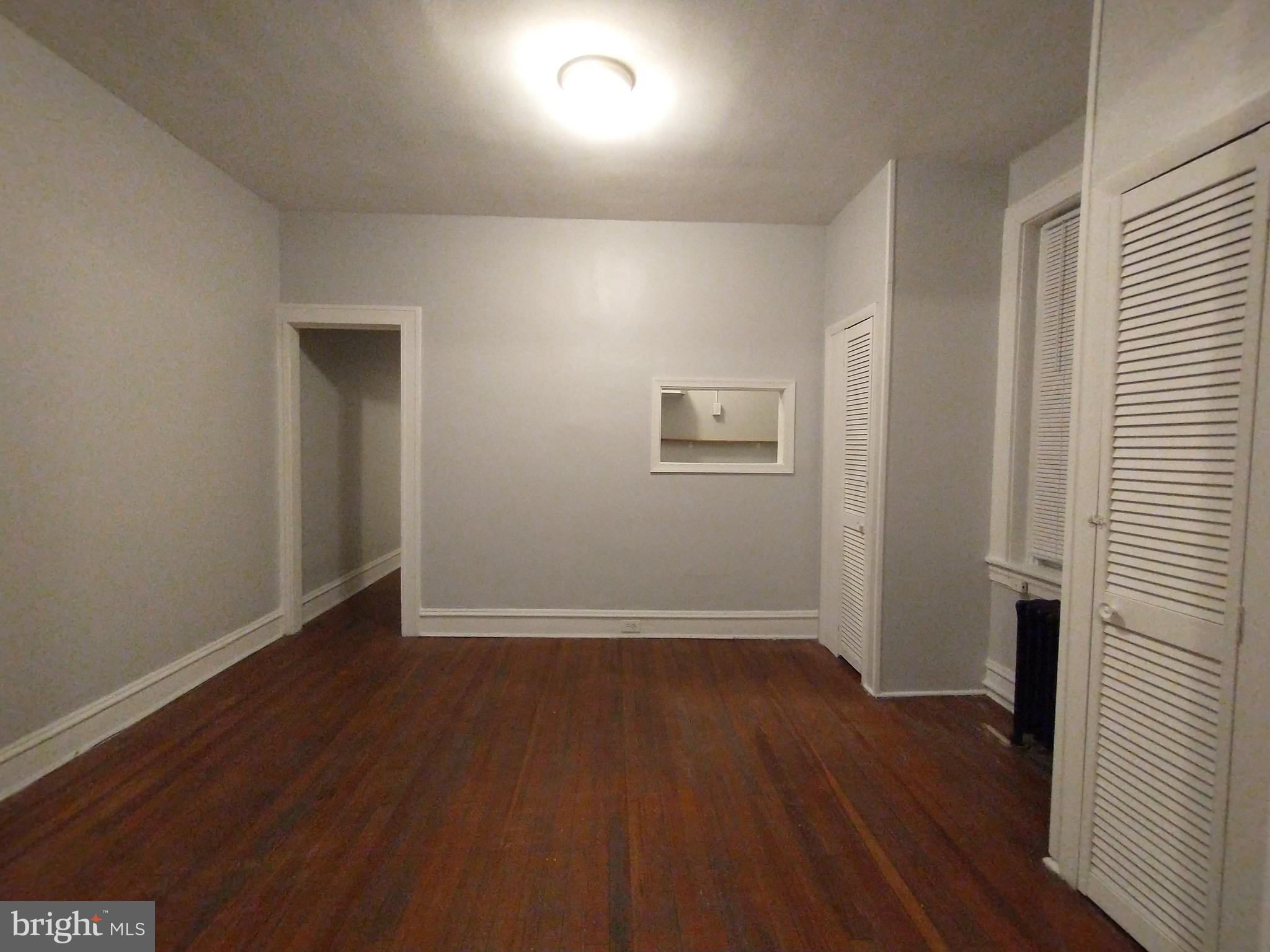 307 Dolphin Street, Unit 3C Baltimore, MD 21201 - Photo 4 of 14 an empty room with wooden floor and windows