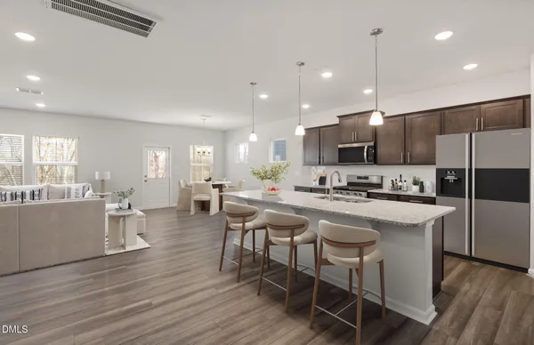 a kitchen with a dining table chairs wooden floor cabinets appliances and a window