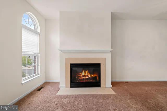 a view of an empty room with a fireplace and a window