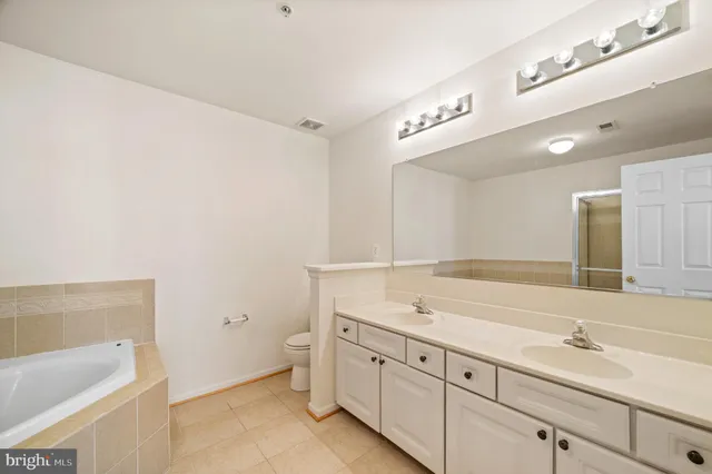 a spacious bathroom with a granite countertop sink and a bathtub