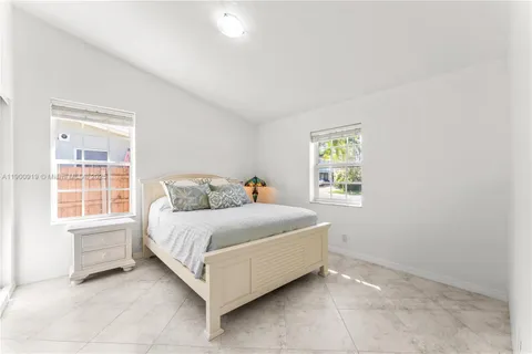 a bedroom with a bed lamp and a large window