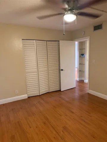 an empty room with wooden floor chandelier fan and windows