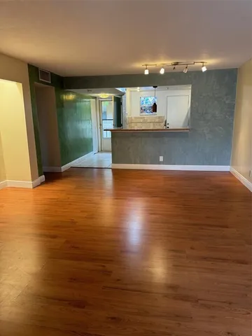 a view of a kitchen with kitchen island a sink wooden floor and a large window