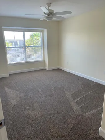 an empty room with windows and fan