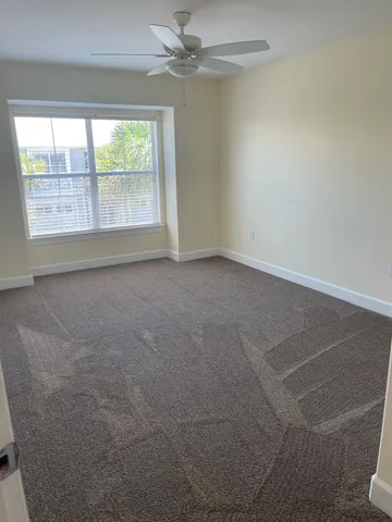 an empty room with windows and fan