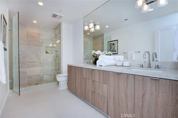 a bathroom with a double vanity sink mirror double shower and a toilet