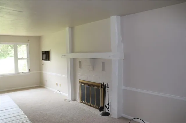 a view of an empty room with a fireplace and a window
