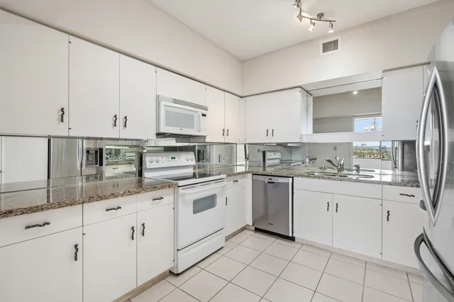 a kitchen with granite countertop white cabinets white stainless steel appliances with a sink and dishwasher