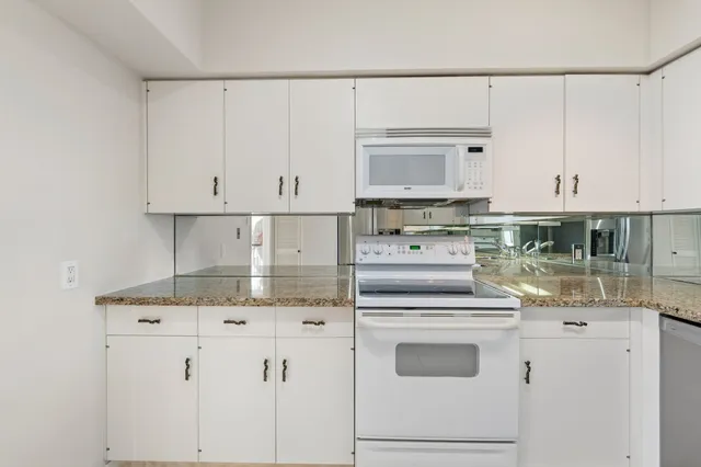 a kitchen with granite countertop white cabinets and white appliances