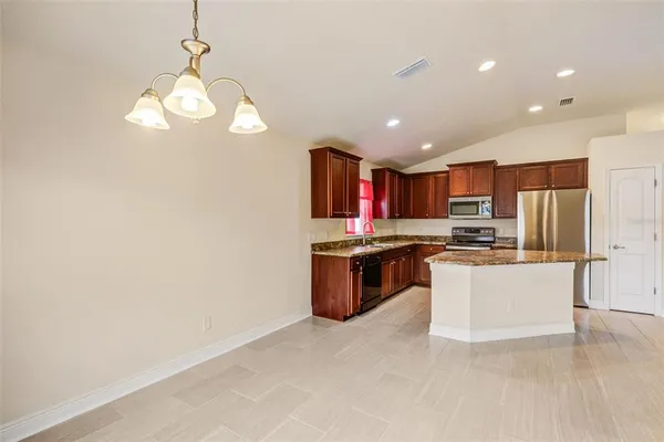 a kitchen with stainless steel appliances granite countertop a refrigerator a sink dishwasher a oven and a dining table with wooden floor