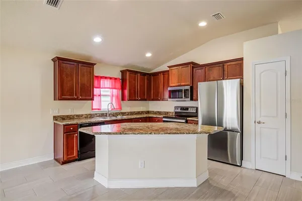 a kitchen with stainless steel appliances granite countertop a stove a refrigerator and a sink with wooden cabinets
