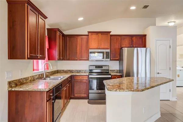 a kitchen with stainless steel appliances granite countertop a sink stove and refrigerator
