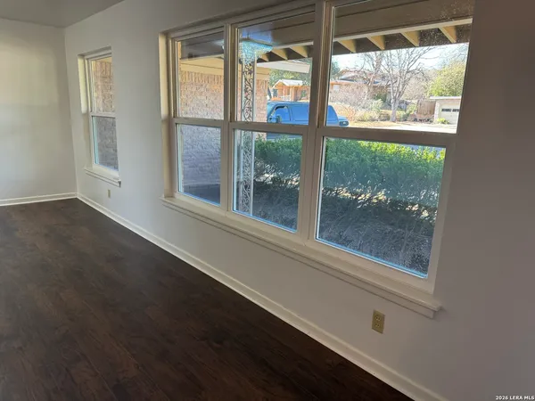 an empty room with wooden floor and windows
