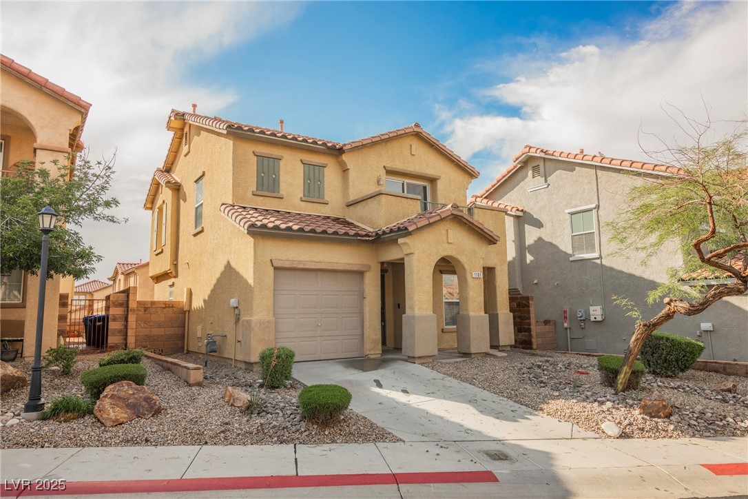 Mediterranean / spanish home with stucco siding, a tiled roof, a garage, and driveway