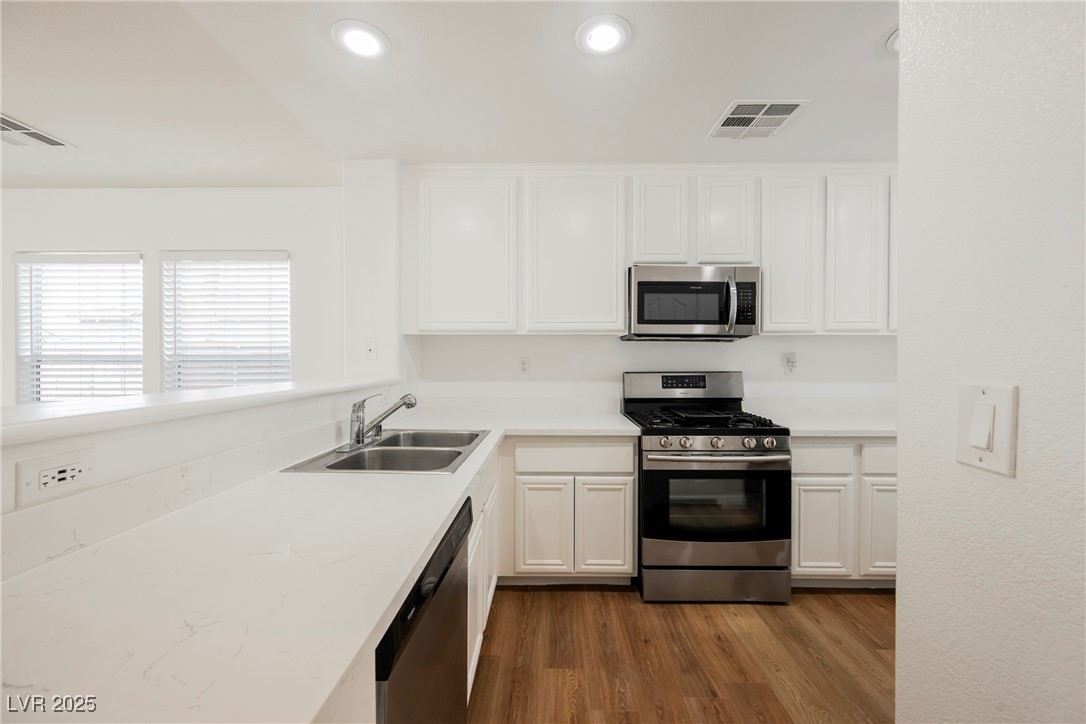 1161 Gecko Road Henderson, NV 89002 - Photo 17 of 54 Kitchen with appliances with stainless steel finishes, dark wood-style floors, white cabinets, and recessed lighting