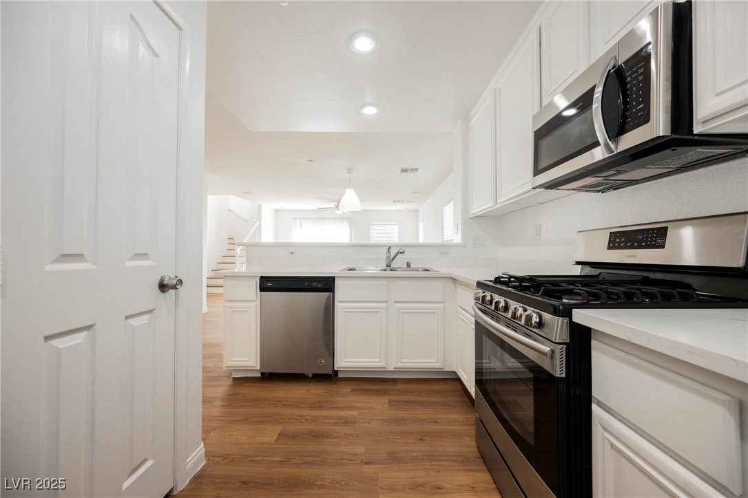 1161 Gecko Road Henderson, NV 89002 - Photo 23 of 54 Kitchen with appliances with stainless steel finishes, dark wood finished floors, white cabinetry, light countertops, and a peninsula