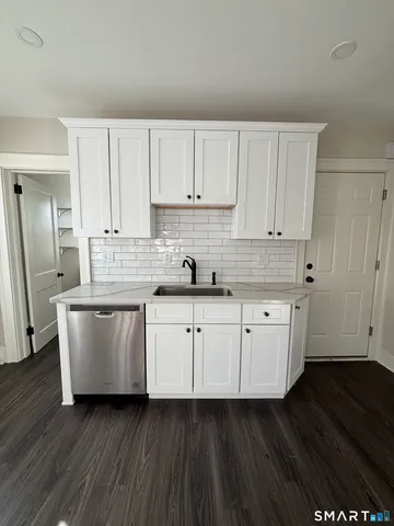 a kitchen with stainless steel appliances granite countertop a white cabinets a sink and dishwasher with wooden floor
